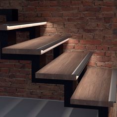 a set of three wooden shelves next to a brick wall with light coming from them