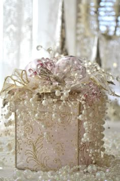 a small box with pearls and flowers on it sitting on a table next to other decorations