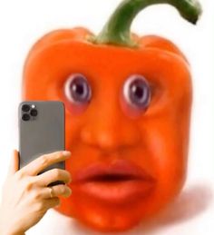 a person holding up a cell phone in front of a pumpkin with eyes on it