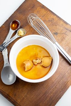 a bowl of soup with spoons and whisks on a wooden cutting board