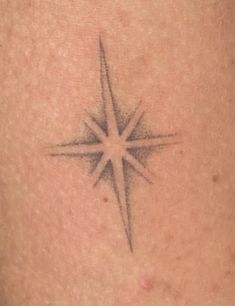 a small tattoo on the back of a woman's shoulder with a star in it