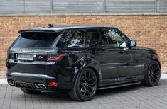 a black range rover parked in front of a brick wall