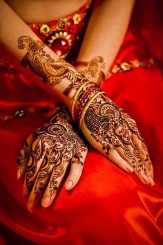 a woman's hands with hennap on her hand and red satin dress