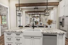 a large kitchen with white cabinets and granite counter tops, an island style sink is in the center of the room