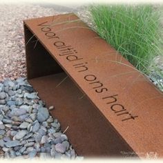 there is a sign that says victory on the side of a bench next to some rocks and grass