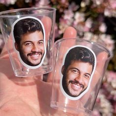 two plastic cups with pictures of the same man and woman on them are shown in front of pink flowers