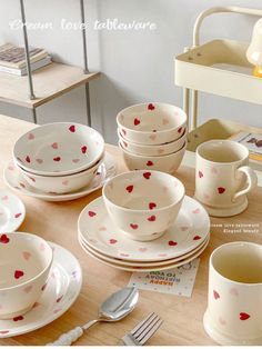 a table topped with lots of white dishes and cups filled with hearts painted on them