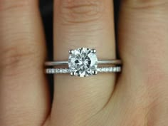 a woman's hand with a diamond ring on top of her finger and the engagement band