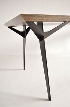 a wooden table sitting on top of a white floor next to a black metal frame