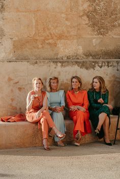 four women are sitting on a stone bench