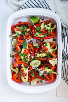 a white casserole dish filled with peppers, avocado and cilantro