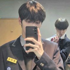 a man taking a selfie with his cell phone in front of him and another person behind him