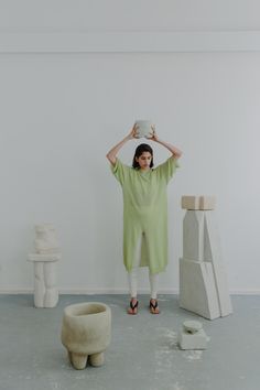 a woman standing in front of sculptures holding a cup above her head and looking at the camera