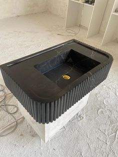 an unusual black and white marble sink in the middle of a room with wires on the floor