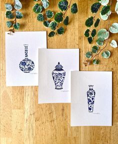 three cards with blue and white vases on them next to some green plant leaves