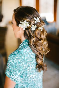 a woman with long hair and flowers in her hair is wearing a blue dress, looking off to the side