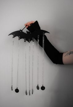 a hand holding a bat with five necklaces hanging from it's back and four dangling bats attached to the side