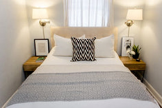 a bed with white sheets and pillows in a bedroom next to two lamps on either side of the bed