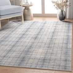 a blue and white rug in a living room next to a chair with a vase on the floor