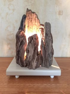 a piece of wood that is on top of a white stand with a fire in it