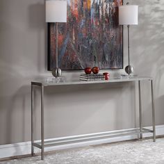 a console table with two lamps on each side and a painting behind it in the corner