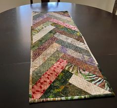 a quilted table runner sitting on top of a wooden table next to a chair