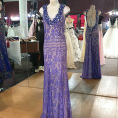 a purple dress on display in front of a mirror at a bridal shop with mannequins and dresses behind it