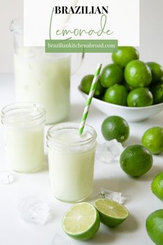 a bowl of limes next to a glass of lemonade with a straw in it