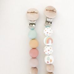 two wooden pegs with different colored beads attached to them on a white surface next to each other