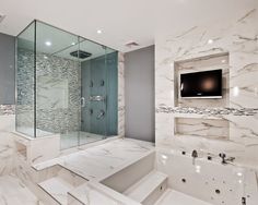 a bathroom with marble walls and flooring has a tv mounted on the wall above the bathtub