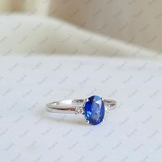 an oval shaped blue sapphire and diamond ring on a white surface with diamonds around it