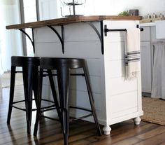 a kitchen island with three stools next to it on a hard wood flooring