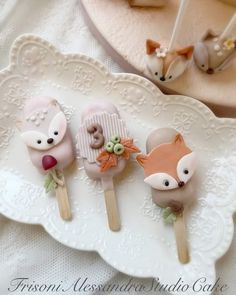 three little foxes are sitting on top of some cake pops with fake flowers and leaves