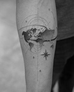 a man's arm with a world map tattoo on it, and compasss