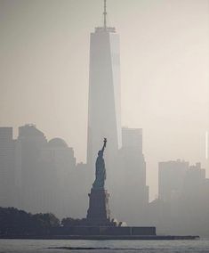 the statue of liberty is surrounded by fog and skyscrapers in new york city, ny