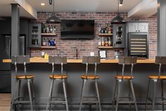 a bar with four stools in front of it and a television on the wall