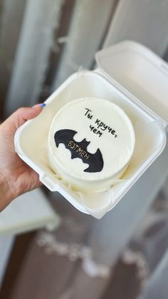 a person holding up a cake in a box with the words to you we bat on it