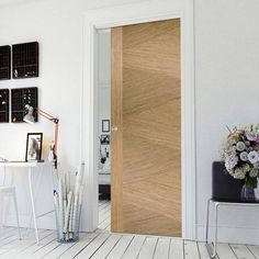 a white room with a wooden door and flowers on the table in front of it