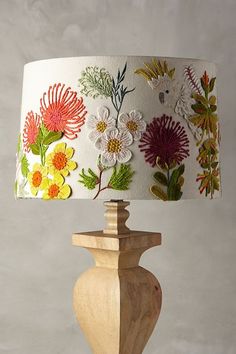 a lamp that is sitting on top of a table next to a wooden base with flowers painted on it