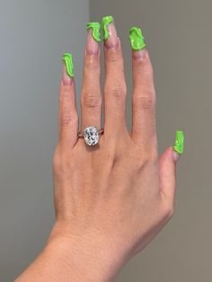 a woman's hand with green nail polish and a diamond ring