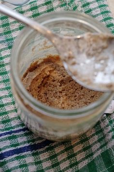 a spoon with some food in it on top of a checkered table cloth next to a jar