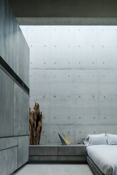 a bed sitting in the middle of a room next to a concrete wall and floor