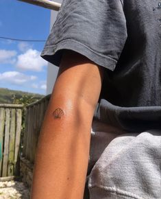 a person with a small tattoo on their left arm and the other arm behind him