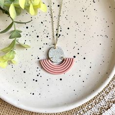 a white plate with a pink and grey necklace on it