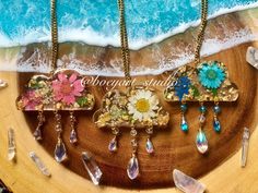 three pieces of jewelry sitting on top of a wooden table next to the ocean and beach