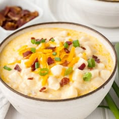 a bowl of potato soup with bacon, cheese and green onions on the side for garnish