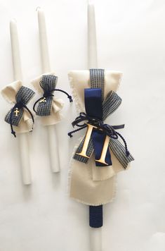 two white candles with blue ribbon and gold initial on them, tied to napkins