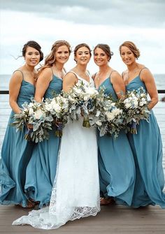 a group of women standing next to each other on top of a wooden floor near the ocean