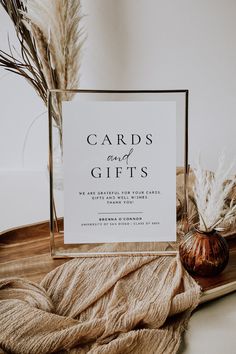 a card and gifts sign sitting on top of a wooden tray next to dried plants