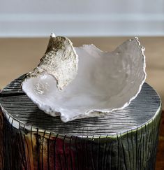 a white bowl sitting on top of a wooden stump